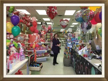A woman standing in front of balloons and gifts.